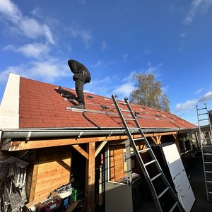Een installateur plaatst zonnepanelen op een hellend dak, met ladders in de buurt voor ondersteuning.