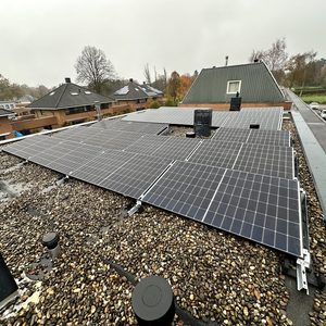Een installatie van zonnepanelen op een plat dak, omgeven door grind, gericht op duurzame energieoplossingen.