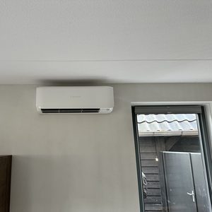 Een moderne airconditioningseenheid is geïnstalleerd aan de muur, ideaal voor het reguleren van de temperatuur in een woonruimte.