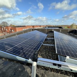 Deze installatie toont zonnepanelen die zijn geplaatst op een plat dak, omringd door grind voor stabiliteit.