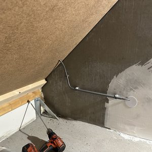 De afbeelding toont een aansluitpunt voor zonnepanelen, met een metallic buis en bevestigingsmateriaal in een werkomgeving.