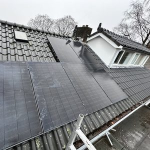Een installatie van zonnepanelen op een dak met een helling. De panelen zijn zichtbaar en goed positioneerd voor zonlicht.