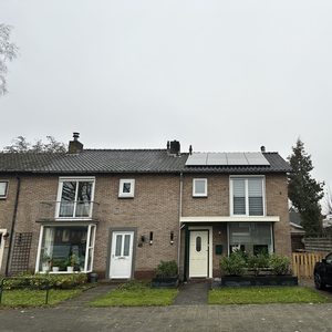 Zonnepanelen zijn geïnstalleerd op het dak van een woning, wat wijst op gebruik van hernieuwbare energie.