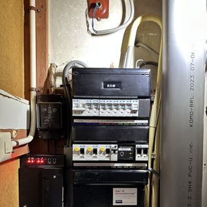 De afbeelding toont een meterkast met diverse elektrische componenten, inclusief een Enphase-apparaat, dat mogelijk gerelateerd is aan een zonnepaneleninstallatie.