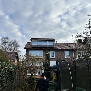 De foto toont een woning met zonnepanelen op het dak, geïnstalleerd in een residentiële omgeving.