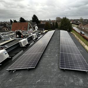 Installatie van zonnepanelen op een plat dak, met een technicus die werkt aan de montage.