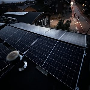 De afbeelding toont zonnepanelen op een dak, mooi gepositioneerd om zonlicht te vangen, met een stadsomgeving op de achtergrond.