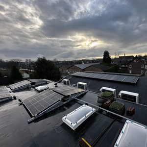 Deze installatie toont zonnepanelen op een plat dak, met uitzicht op een buurt. De panelen zijn strategisch geplaatst voor optimale blootstelling aan zonlicht.