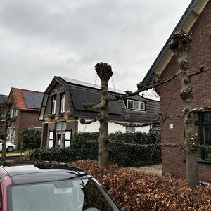 De foto toont een installatie van zonnepanelen op de daken van twee woningen in een straat. De panelen zijn zichtbaar en dragen bij aan duurzame energieproductie.