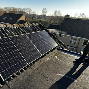 De afbeelding toont een installatie van zonnepanelen op het dak van een woning, gericht op maximale blootstelling aan zonlicht.