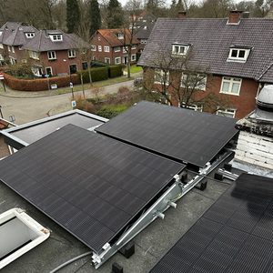 De afbeelding toont een installatie van zonnepanelen op een dak, met meerdere panelen verbonden via een montagesysteem.