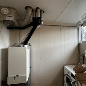 De afbeelding toont een ruimte met verschillende installaties, waaronder een verwarmingsketel en een meterkast, maar geen zonnepanelen.