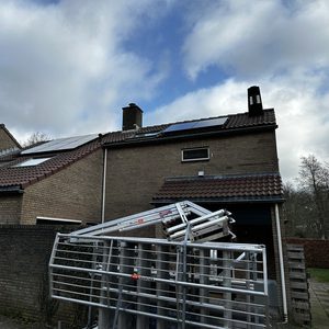 De afbeelding toont zonnepanelen geïnstalleerd op het dak van een woning, met een heldere lucht op de achtergrond.