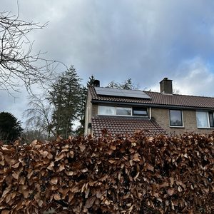 De foto toont een woning met zonnepanelen op het dak, geïntegreerd in de dakconstructie.