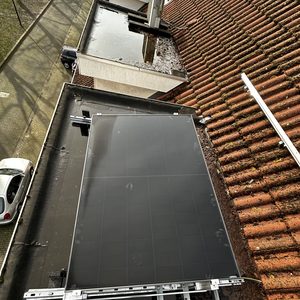 De installatie toont zonnepanelen die op een hellend dak zijn geplaatst, met gereedschap zichtbaar voor de montage.