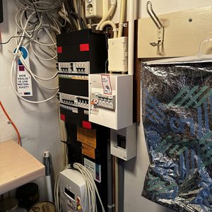 De afbeelding toont een meterkast met diverse schakelaars en bedrading, typisch voor een installatie van zonnepanelen, waaronder de omvormer.