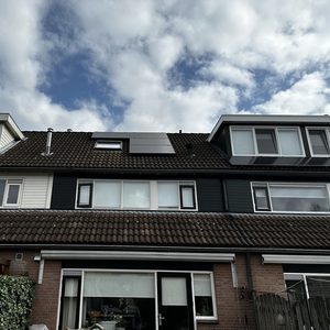 De afbeelding toont zonnepanelen die zijn geïnstalleerd op het dak van een woning, goed zichtbaar in de context van de huisarchitectuur.