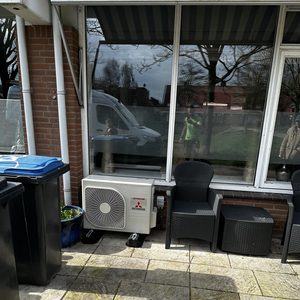 Een airconditioningsysteem is geïnstalleerd buiten, met zichtbare eenheid en leidingen, klaar voor gebruik.