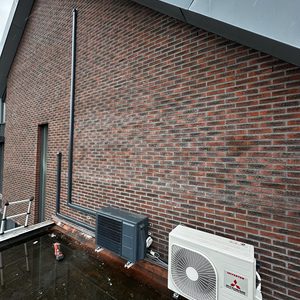 De afbeelding toont een installatie van een airconditioning, met binnen- en buitenunits bevestigd aan de muur.