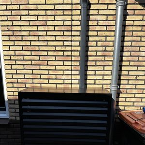 Een buitenunit van een airconditioning systeem, geïnstalleerd tegen een bakstenen muur.
