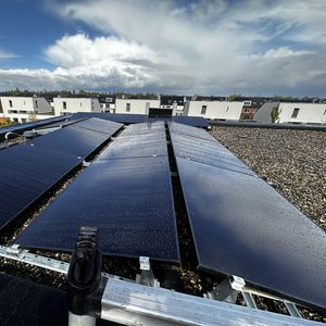 De afbeelding toont een zonnepaneleninstallatie op een plat dak, met zicht op de omgeving en de weersomstandigheden.