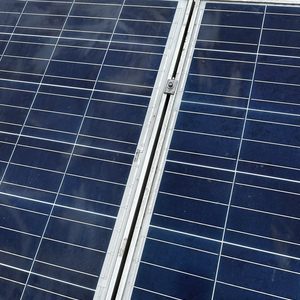 De afbeelding toont een close-up van zonnepanelen met blauwe cellen, duidelijk zichtbaar geïnstalleerd op een ondergrond.