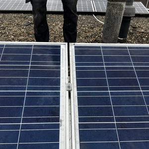 Detail van een zonnepaneleninstallatie, gericht op de verbinding tussen panelen op een grindbed.