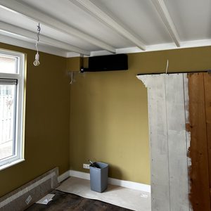De afbeelding toont een net geïnstalleerde airconditioningseenheid aan de muur in een kamer met een eenvoudige afwerking.