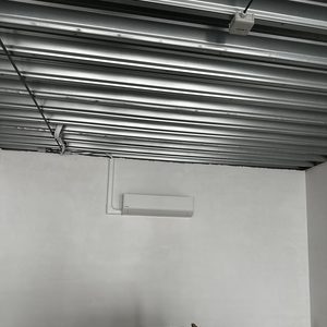 Een recent geïnstalleerde airconditioningseenheid aan de muur in een onafgebouwde ruimte.