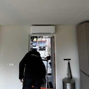 Installatie van een airconditioningsysteem aan het plafond, met een technicus in actie voor een optimale montage.