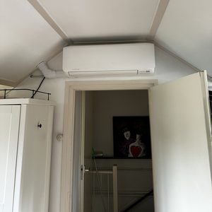 Een wandmodel airconditioningseenheid is geïnstalleerd onder het plafond, geschikt voor klimaatbeheersing in de ruimte.