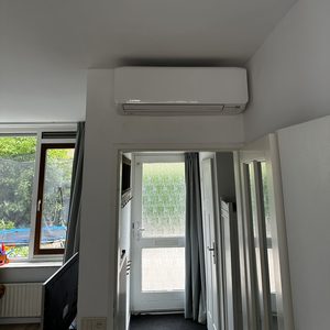 Een binnenunit van een airconditioning systeem, geïnstalleerd aan de muur in een lichte ruimte.