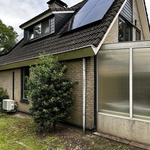 De installatie toonde een airconditioningseenheid aan de buitenzijde van een woning, nabij een set zonnepanelen.