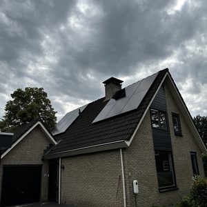 Een woning met zonnepanelen op het dak, geïnstalleerd voor het opwekken van zonne-energie.