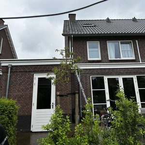 De foto toont een buitenzijde van een woning waar een airco-installatie wordt uitgevoerd met een ladder en een duidelijke ingang.