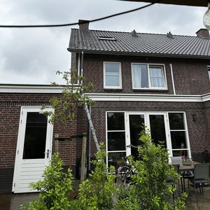De foto toont een woning met een ladder en voorbereidingen voor de installatie van een airconditioning unit aan de buitenkant.