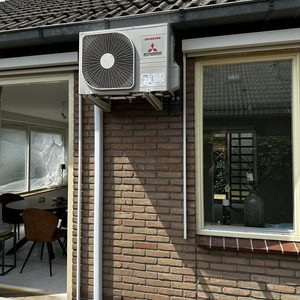 Een buitenunit van een Mitsubishi airconditioningsysteem, geïnstalleerd aan de gevel van een woning.