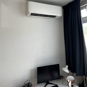 De afbeelding toont een wandmodel airconditioningseenheid gemonteerd aan de muur in een moderne kamer.