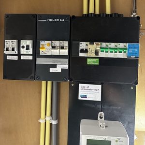 De foto toont een meterkast met diverse schakelaars en beveiligingssystemen voor elektriciteit en gas.