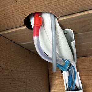 De afbeelding toont een onderdeel van een airconditioninginstallatie met leidingen en aansluitingen door een wandopening.