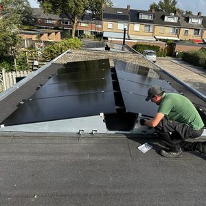 Een installateur bevestigt zonnepanelen op een hellend dak, wat getuigt van een duurzame energieoplossing.