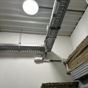 De afbeelding toont de installatie van een airconditioningseenheid met leidingen en montage-elementen in een technische ruimte.