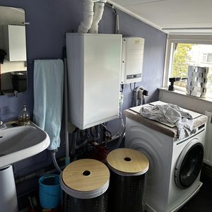 De afbeelding toont een lucht-lucht airconditioningsysteem geïnstalleerd in een kleine ruimte, met leidingen en de unit zichtbaar.