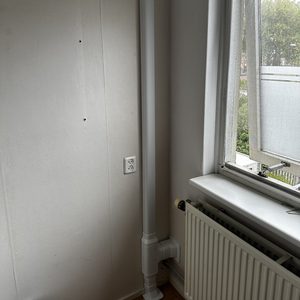 Installatie van een airconditioning systeem met een afvoerpijp. De installatie is opgezet in een ruimte naast een raam.