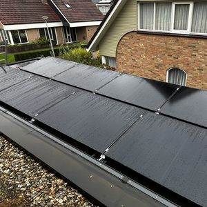 Een reeks zonnepanelen is geïnstalleerd op een dak. De panelen zijn nat, vermoedelijk door recent neerslag, wat hun efficiëntie kan beïnvloeden.