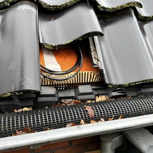 Deze foto toont een deel van een zonnepaneleninstallatie met zichtbare bekabeling en een overhangende dakrand.