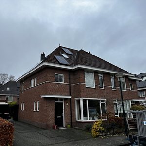 Zonnepanelen zijn geïnstalleerd op het dak van een woning, gericht op het maximaliseren van zonne-energieopbrengst.