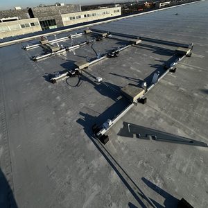 De foto toont een kunststofmontagesysteem voor zonnepanelen op een plat dak. Het systeem is ontworpen om de panelen stevig te bevestigen.