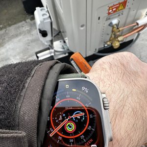 Een airco-installatie in uitvoering, met een foto van een thermostaat op de pols en de buitenunit zichtbaar op de achtergrond.