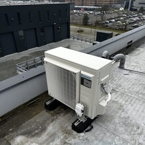 Externe airconditioning unit geïnstalleerd op een plat dak, met voldoende ruimte rondom voor luchtcirculatie.